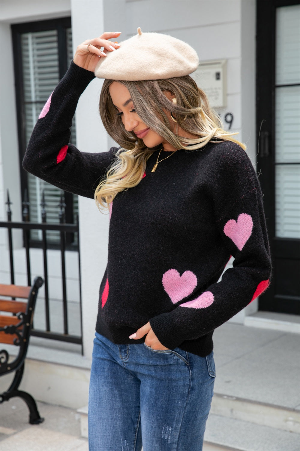 Black crewneck sweater with pink and red intarsia hearts, long sleeves.