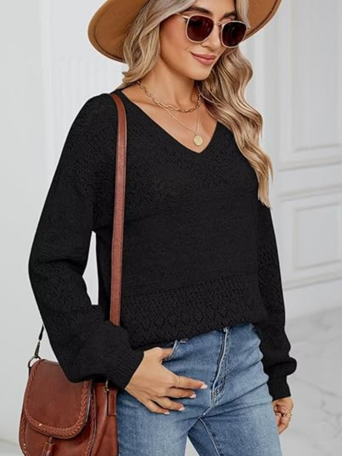 Black eyelet stitch V-neck pullover sweater with long sleeves and textured knit details.