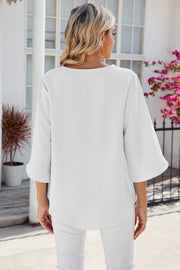 White asymmetric sleeve blouse with relaxed fit and bell sleeves.