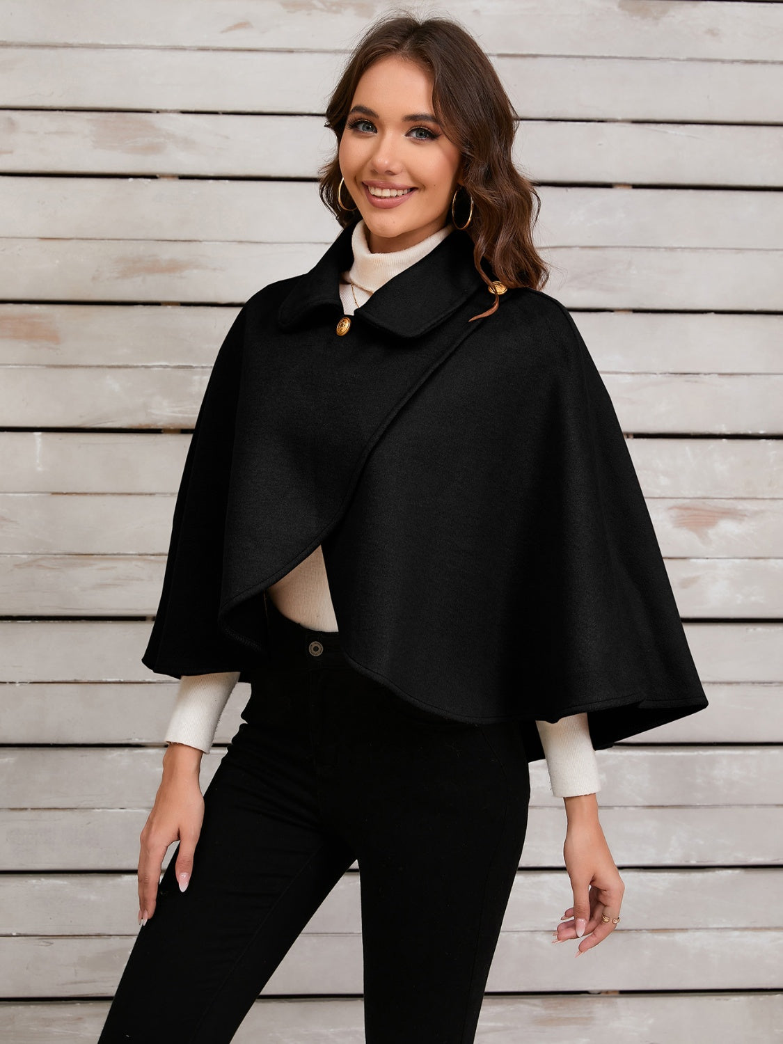 Black asymmetric button-front cape jacket with gold buttons and a collar.