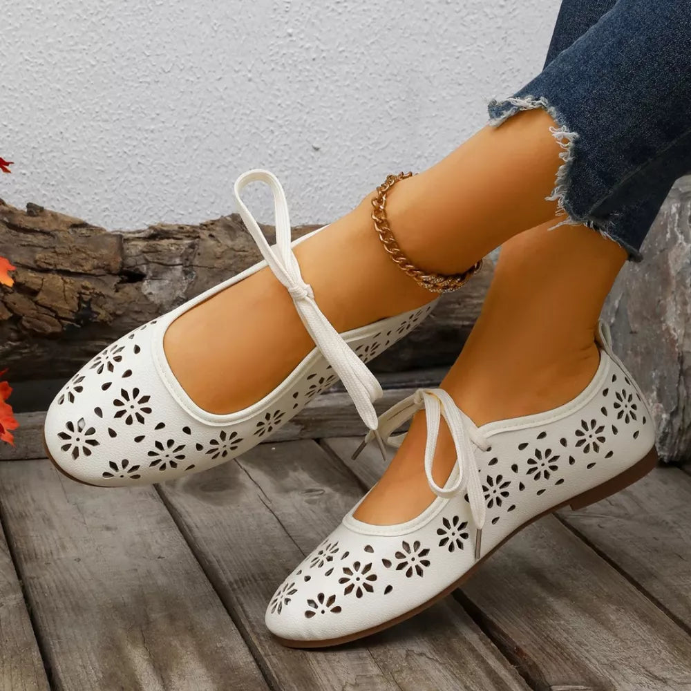White floral cutout slip-on flats with tie ankle straps and a round toe.