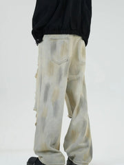 Distressed wide-leg jeans in Yellow Mud with a tie-dye effect and ripped details.