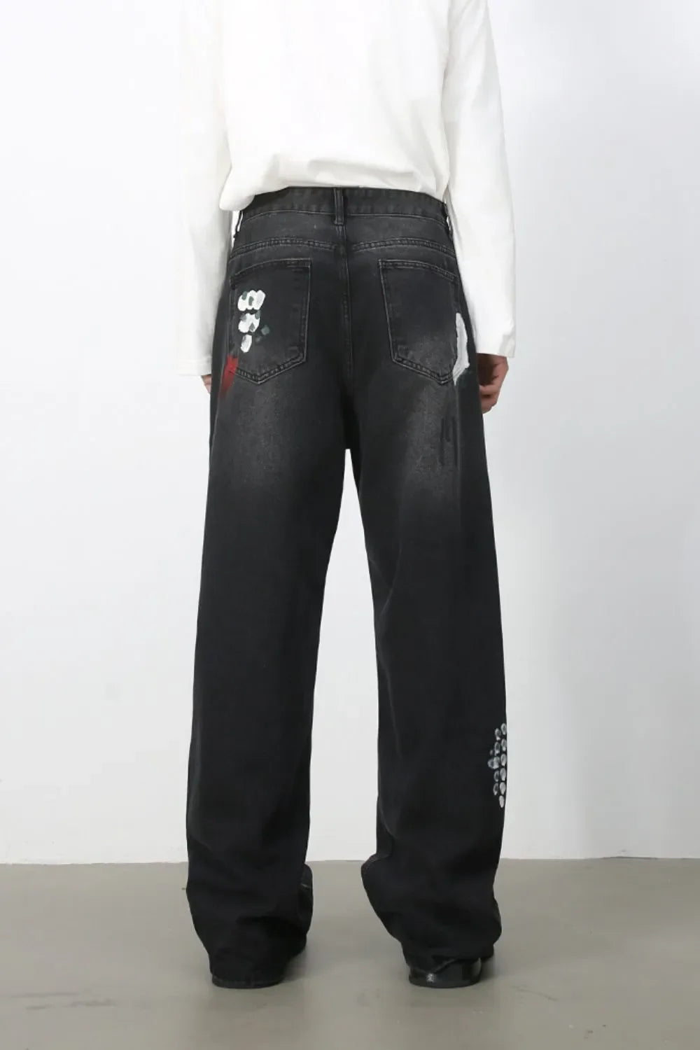 Dark wide-leg jeans with painterly brushstroke details and distressed accents.
