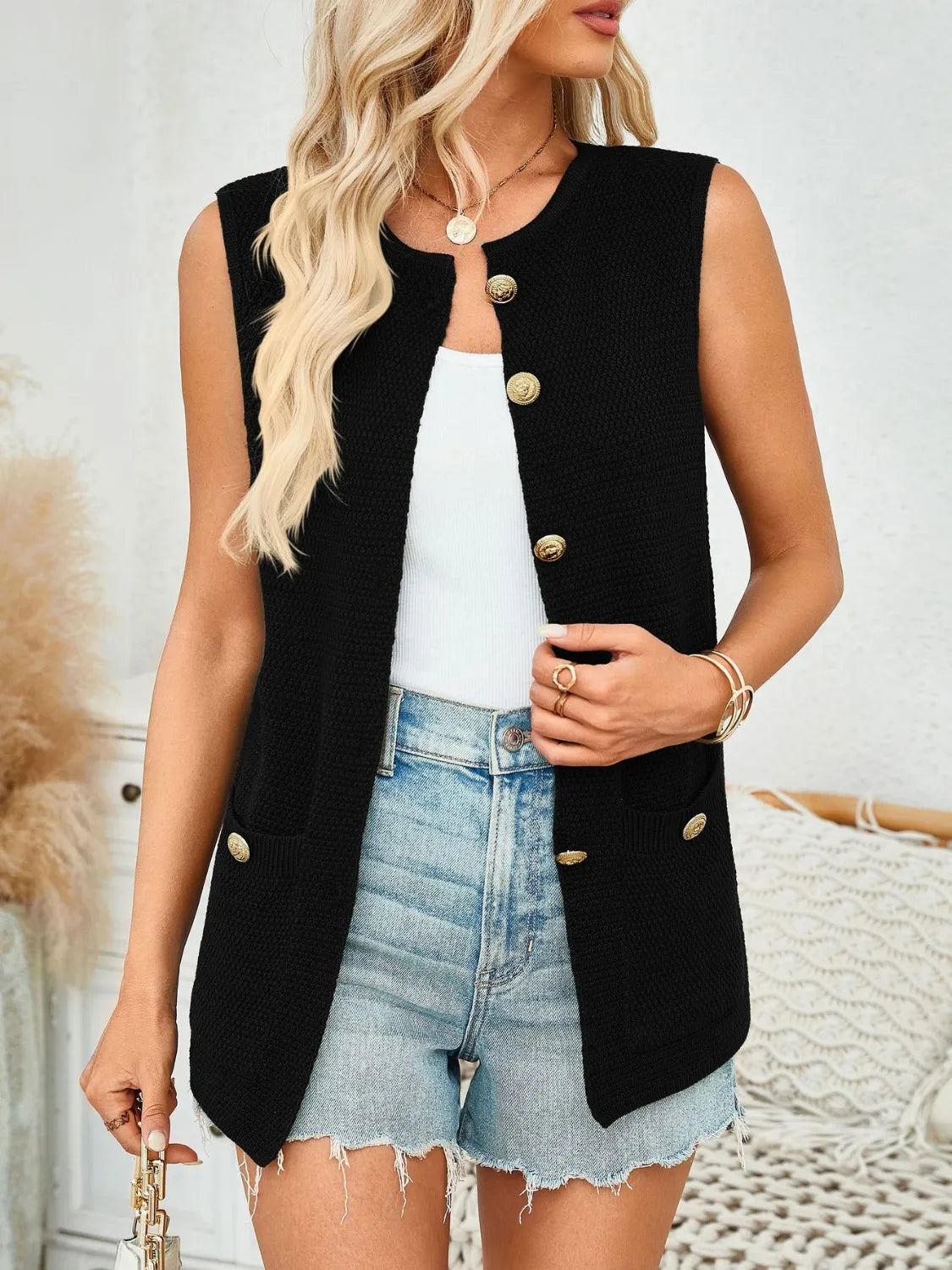 Black knit buttoned vest with gold buttons and pocket details
