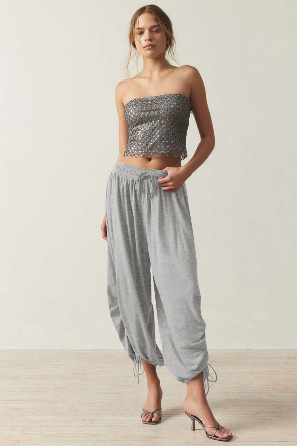 Gray balloon trousers with gathered ankle ties and drawstring waist.