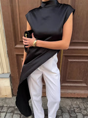 Black cap sleeve turtleneck blouse with asymmetrical hem and high neck.
