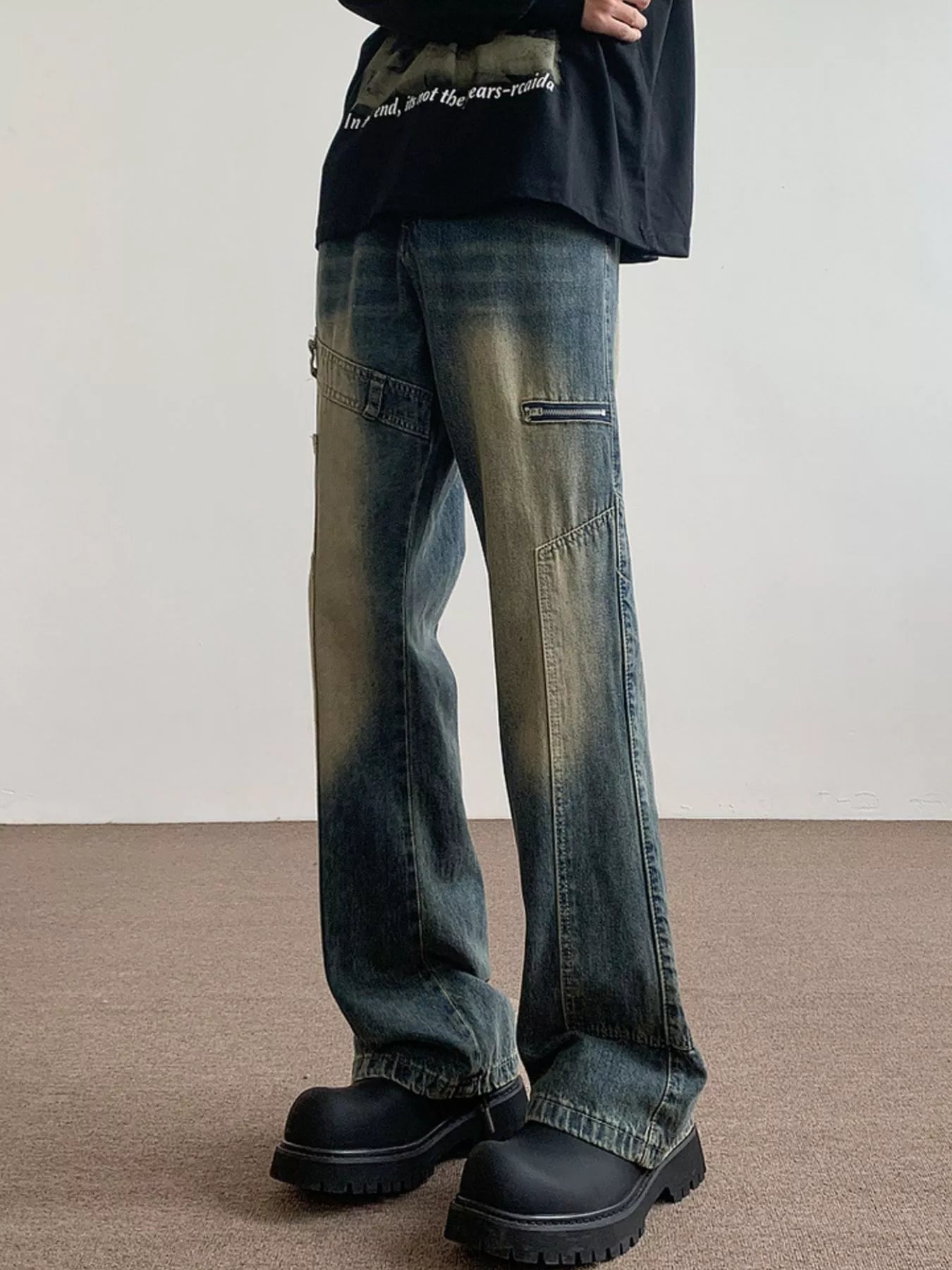 Men's blue vintage wash flare jeans with distressed details and zipper pockets.