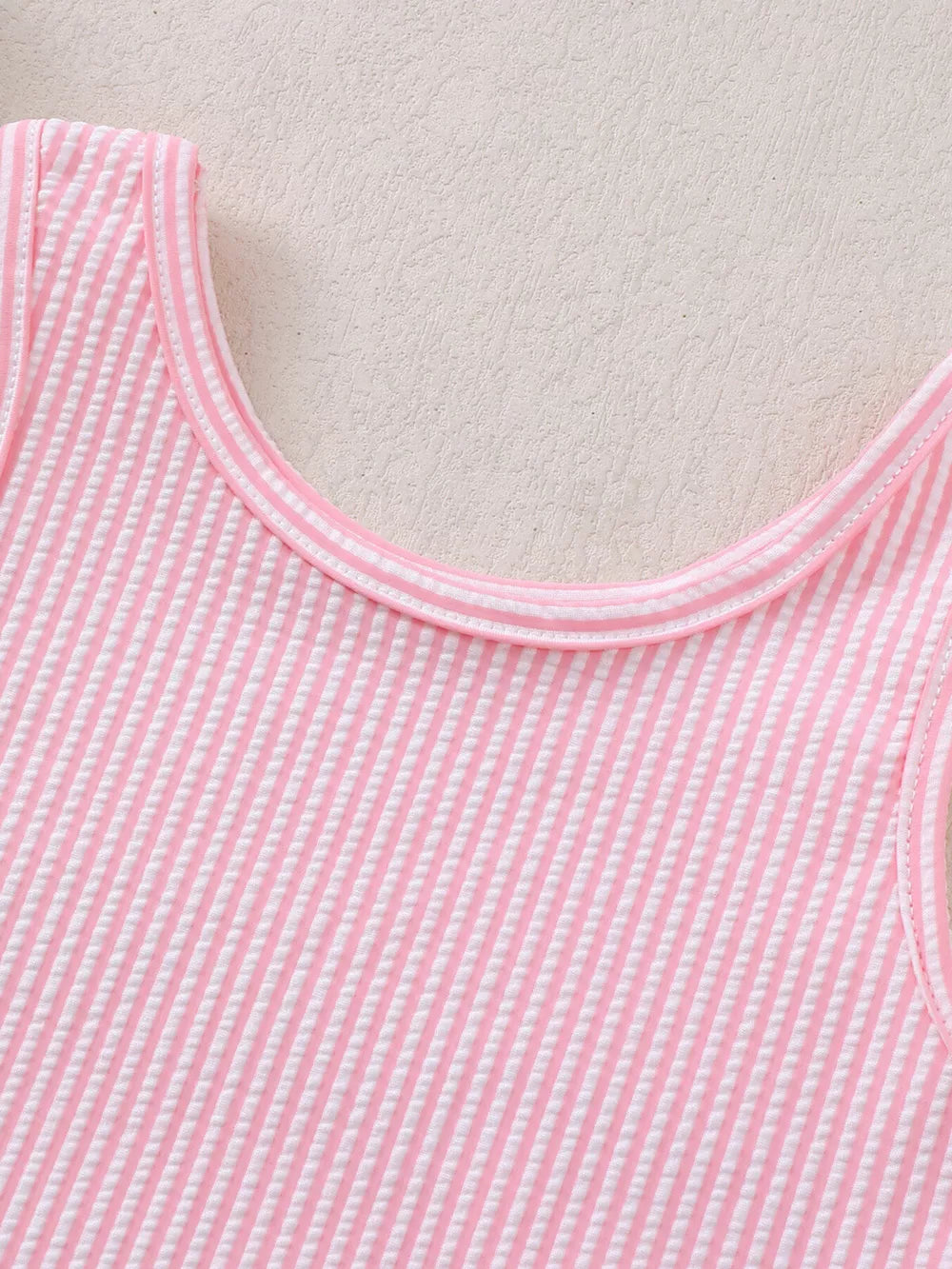Pink striped seersucker one-piece swimsuit with ruffled trim.