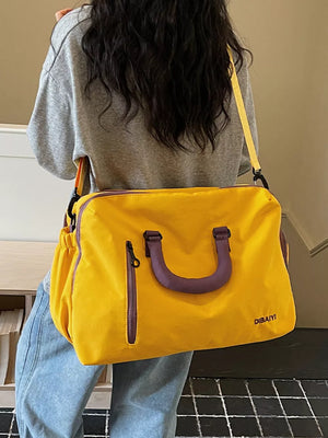 Yellow travel organizer bag with purple handles and zipper accents, adjustable strap.