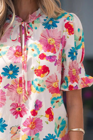 Vibrant floral print shirt with tie neck, ruched short sleeves, and smocked cuffs.