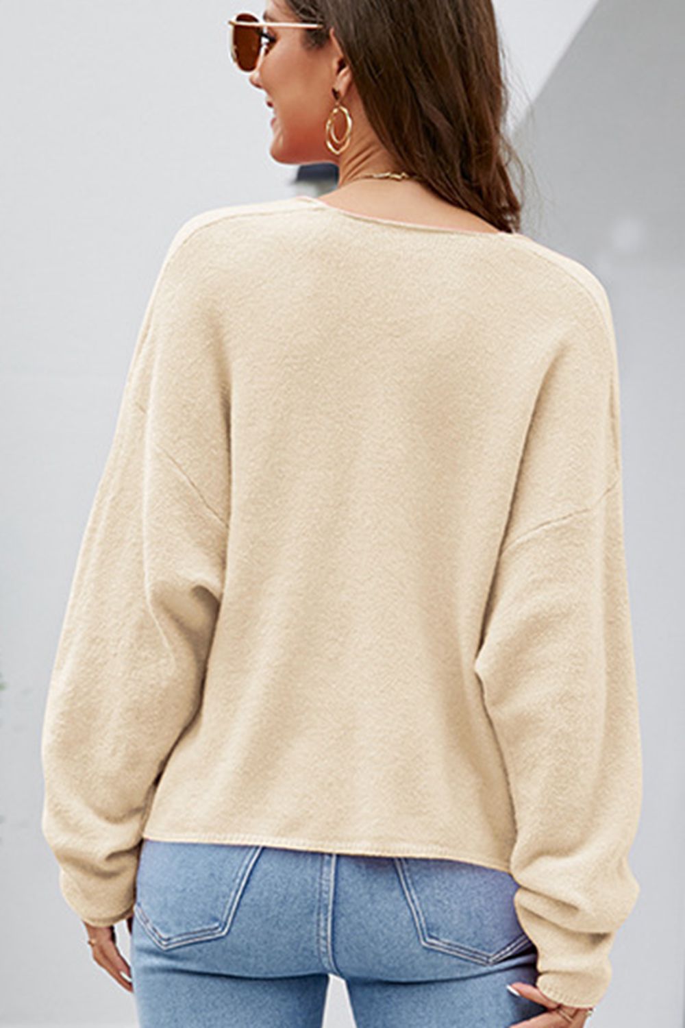 Tan textured knit pullover sweater with a deep V-neck and long sleeves.