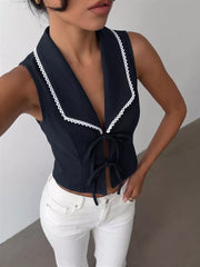 Navy vest with white lace trim and tie front, styled with white jeans.