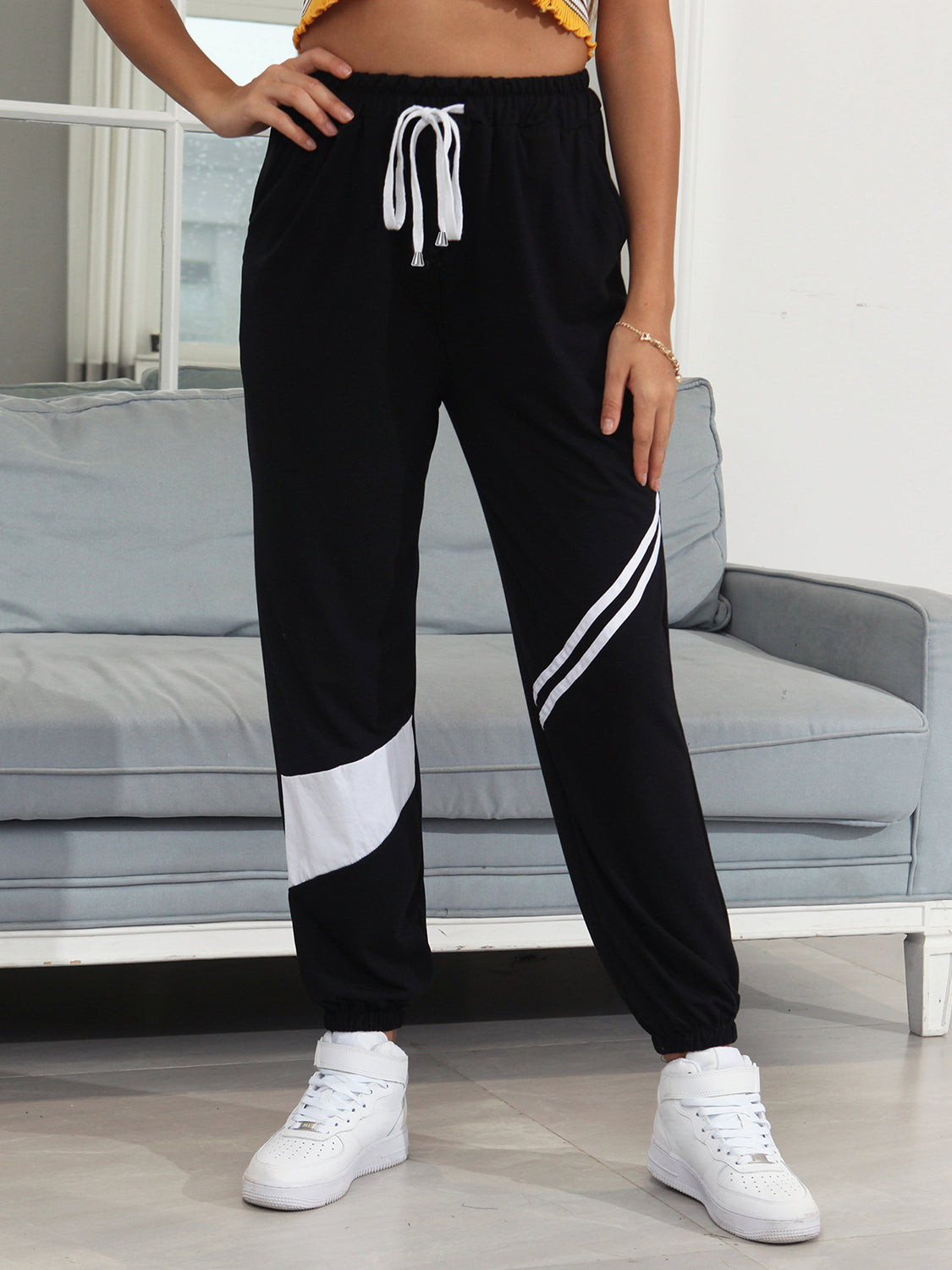Black joggers with white diagonal panel details and drawstring waist.