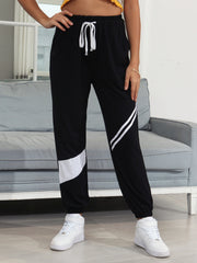 Black joggers with white diagonal panel details and drawstring waist.