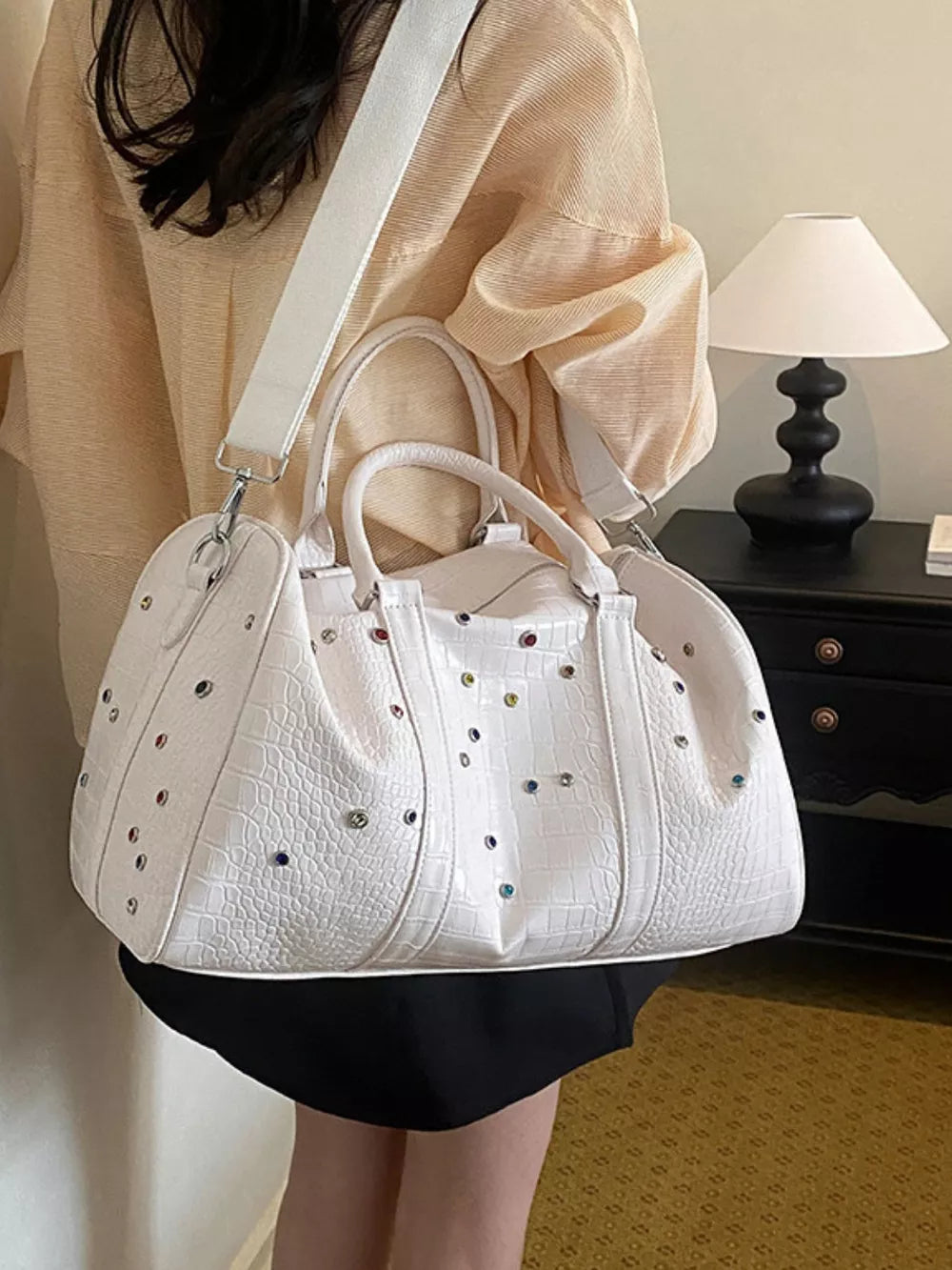 White crocodile textured duffel bag with colorful studs and detachable strap