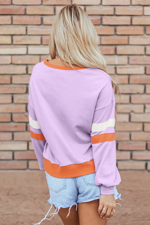 Lavender sweatshirt with orange and cream stripe details on sleeves and contrast trim.