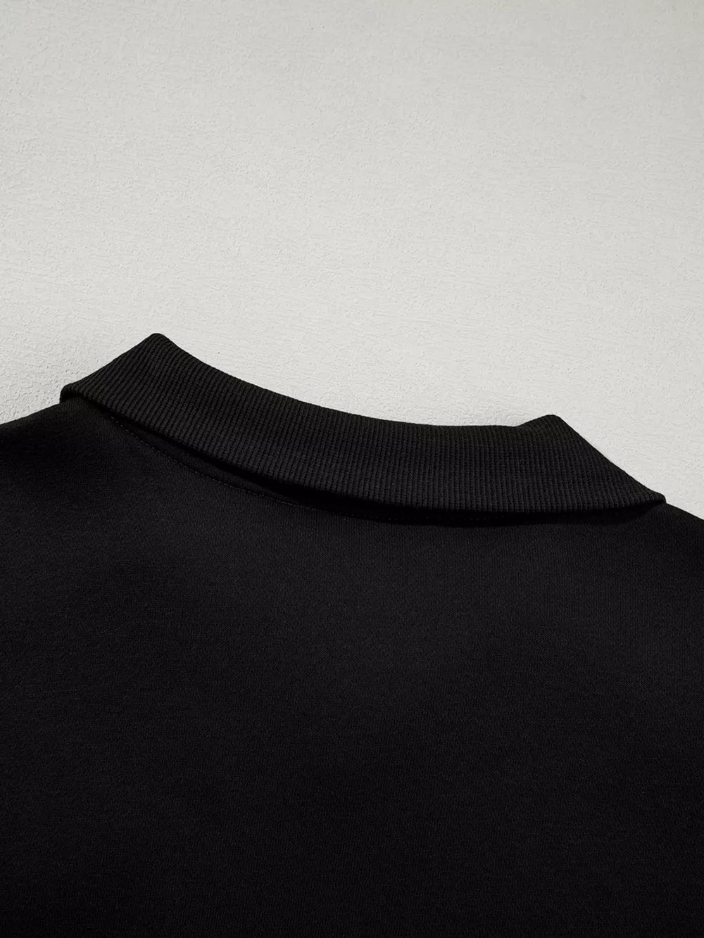 Black zip-up jacket collar detail with ribbed trim, comfortable cotton activewear.