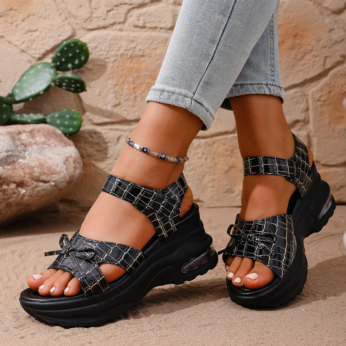 Black textured open-toe wedge sandals with adjustable straps and bow detail.