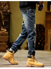 Blue distressed slim fit jeans with embroidered accents and cuffed hems.