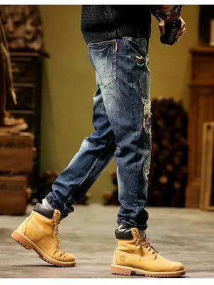 Blue distressed slim fit jeans with embroidered accents and cuffed hems.