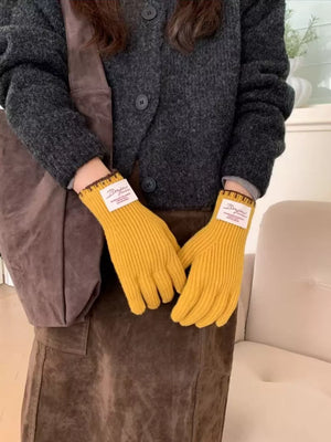 Yellow ribbed knit gloves with scalloped cuff and embroidered label detail.