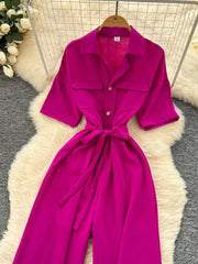 Belted wide-leg jumpsuit in pink with short sleeves, collar, button front, and tie waist.