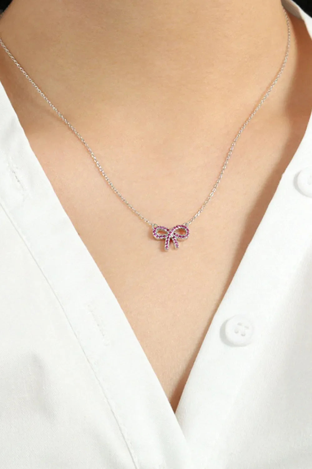 Silver necklace with ruby-embellished bow pendant
