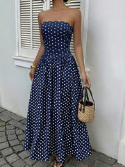 Navy polka dot A-line maxi dress with strapless neckline and cinched waist.