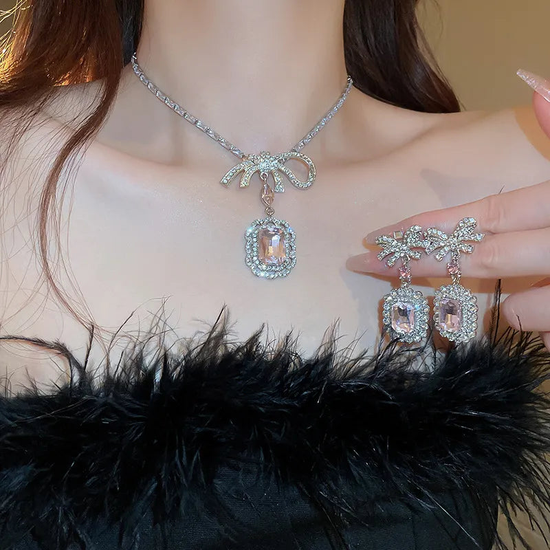 Silver bow pendant necklace with crystal drop and matching earrings.