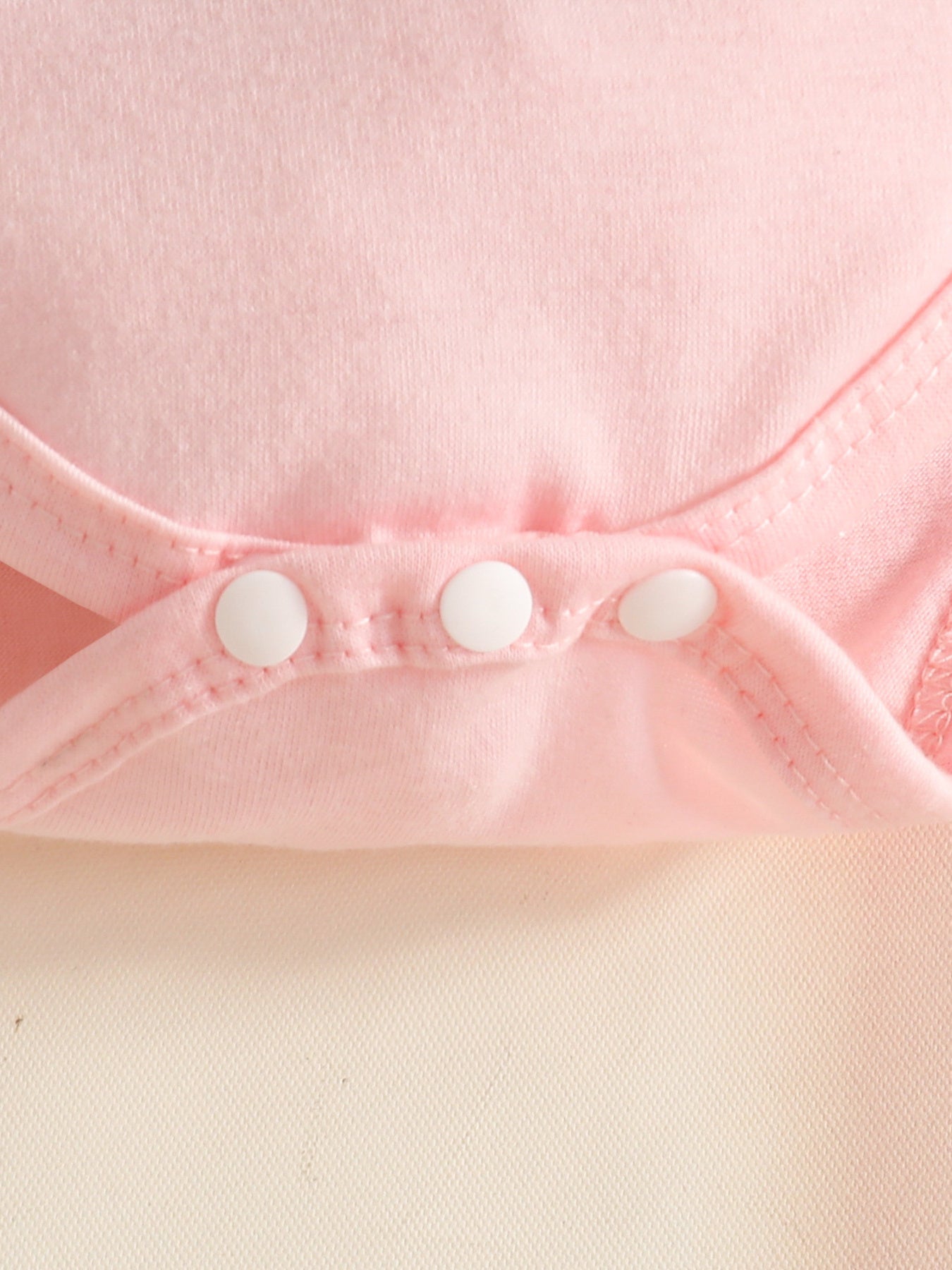 Pink baby bodysuit with white snap closures
