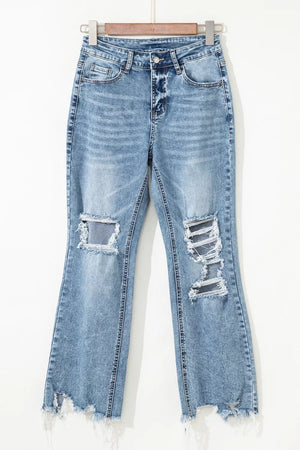 Distressed light wash denim flare jeans with open knees and raw hem.