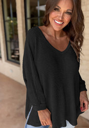 Black waffle knit V-neck top with slit hem and long sleeves.