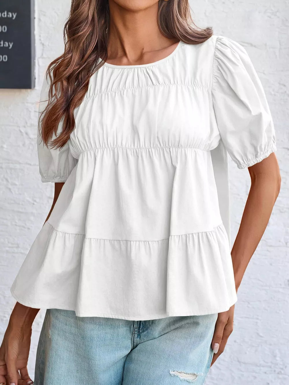 White maternity blouse with puff sleeves, ruffled tiers, and smocked bodice detail.