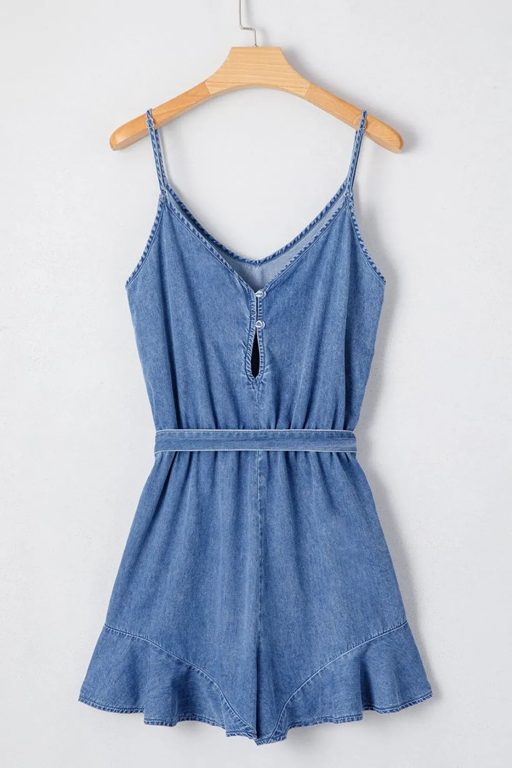 Medium denim romper with spaghetti straps, tie waist, and ruffled hem