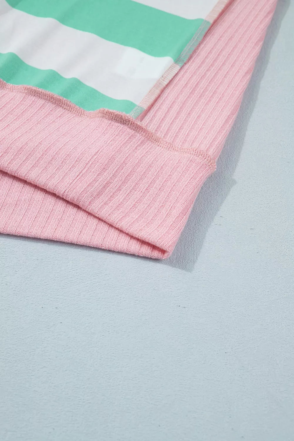 Oversized t-shirt with horizontal stripes in green and white, and pink ribbed cuffs and hem.