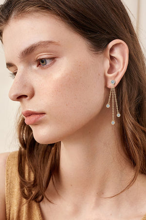 Gold cascading crystal chain drop earrings with three dangling charms.