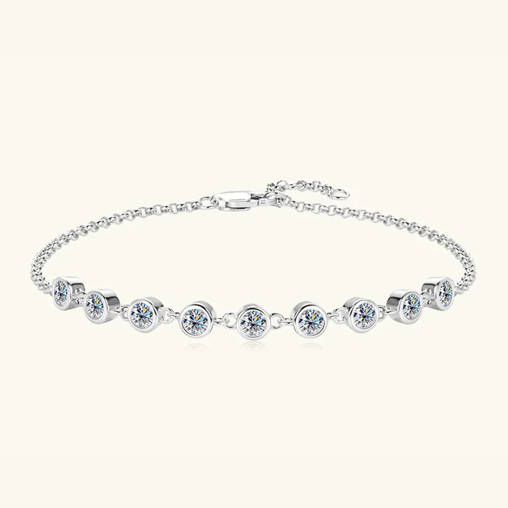 Silver bezel-set moissanite tennis bracelet with a delicate chain and clasp.