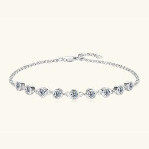 Silver bezel-set moissanite tennis bracelet with a delicate chain and clasp.