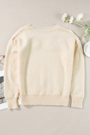 Tan knit sweater with embroidered floral appliqué, crew neck, long sleeves, ribbed cuffs and hem.