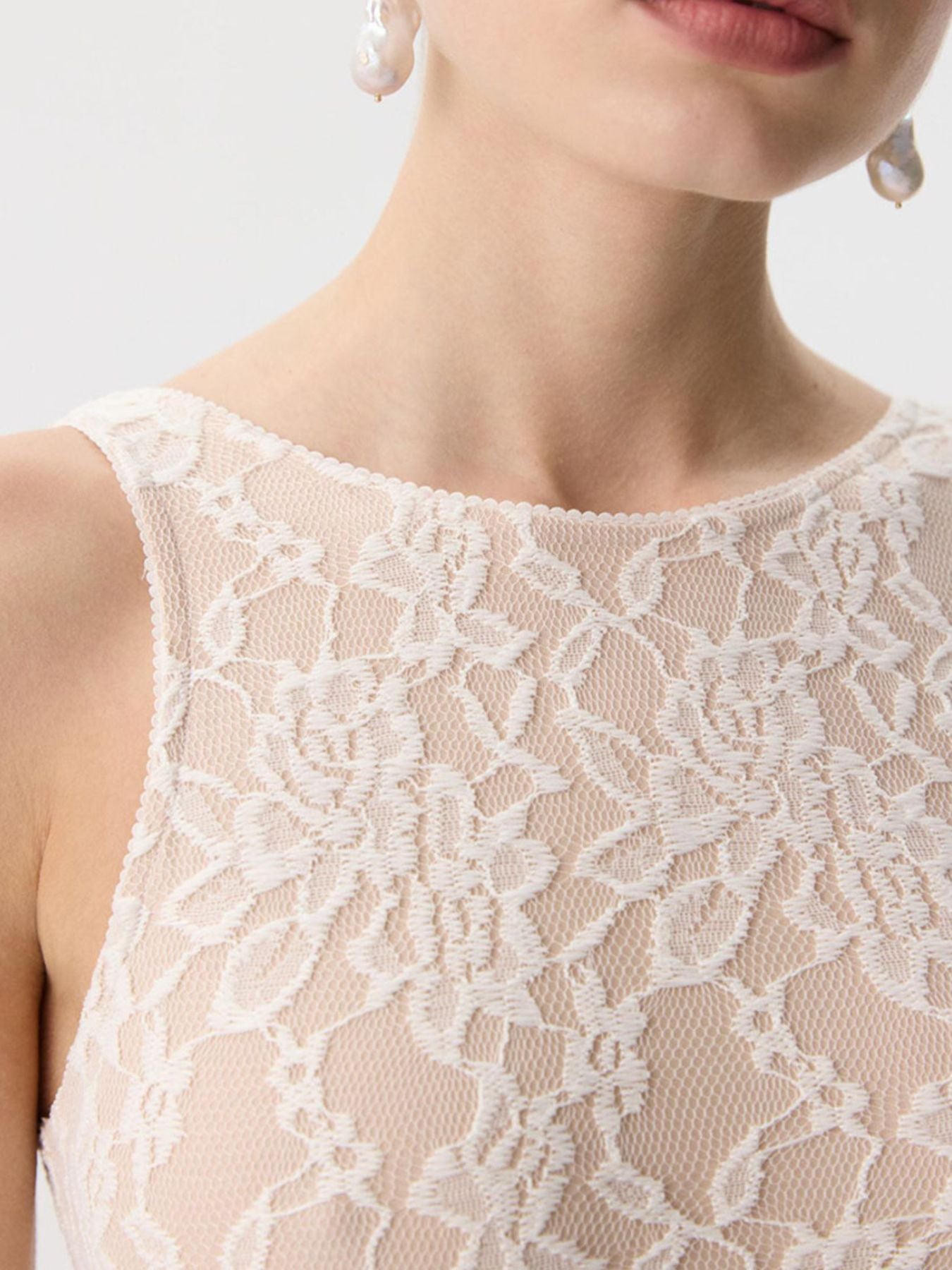 Beige sheer lace tank top with floral pattern and scalloped neckline.