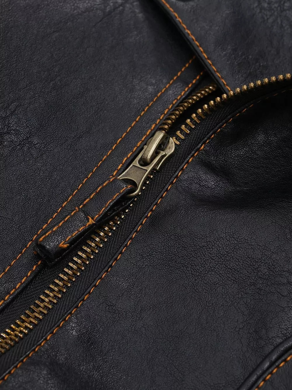 Black faux leather motorcycle coat detail with brass zipper and contrast stitching.