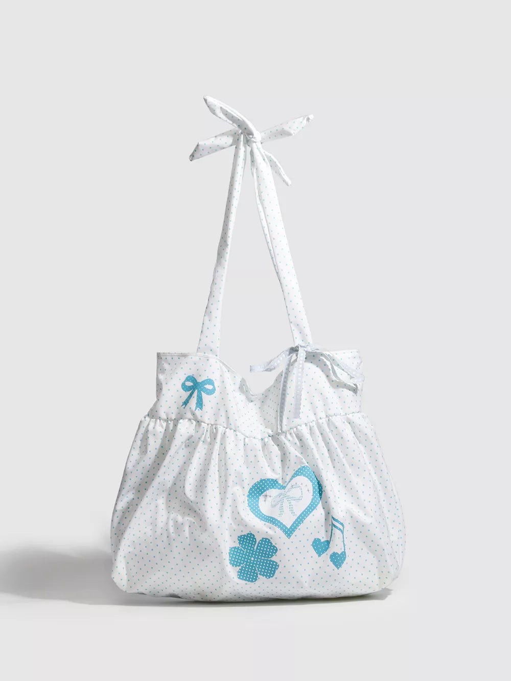 Pastel blue polka dot canvas shoulder bag with heart, clover, and music note appliqués and bow details.