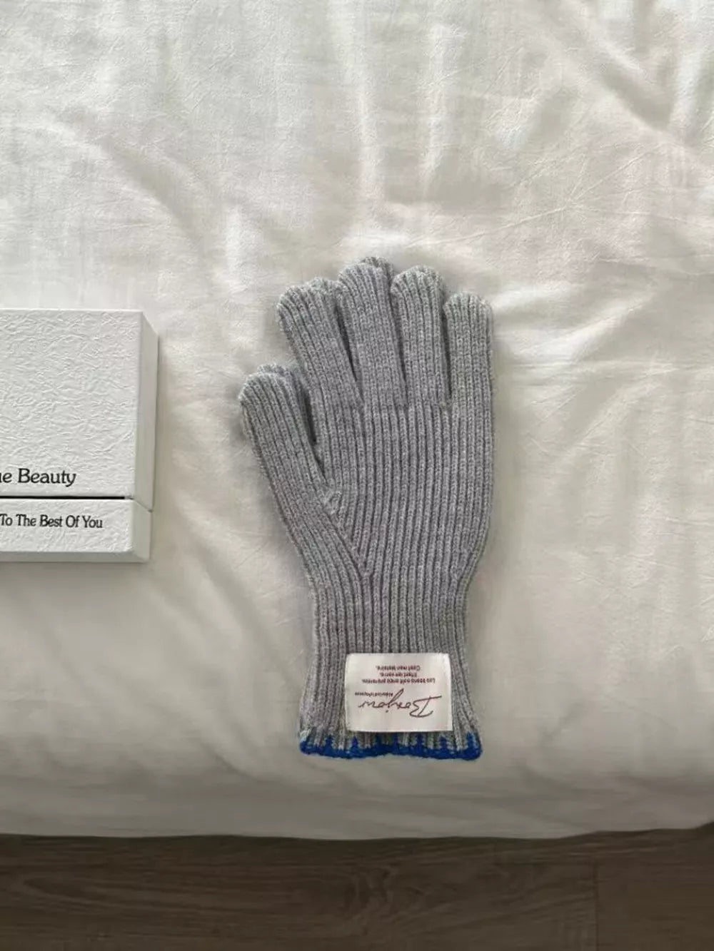 Gray ribbed knit gloves with blue trim and a decorative tag.