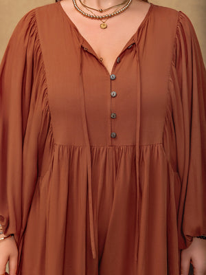 Caramel romper with voluminous sleeves, tiered skirt, and buttoned neckline with tie detail.