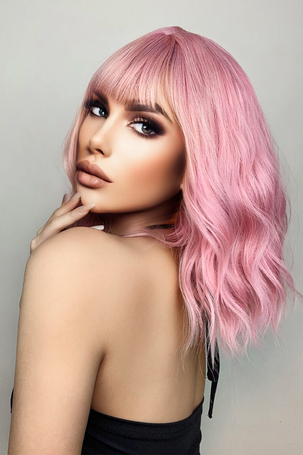 Pink bob wig with bangs and loose waves, styled casually.