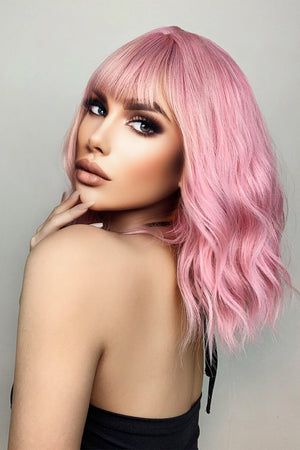Pink bob wig with bangs and loose waves, styled casually.