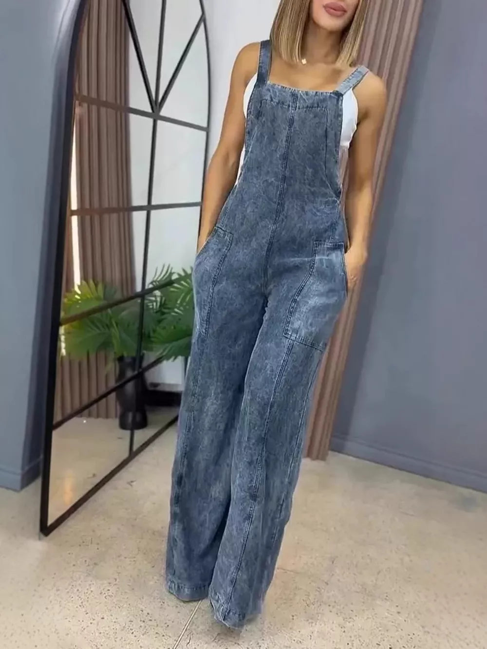 Vintage wash wide-leg denim overalls in blue with bib front and pockets.