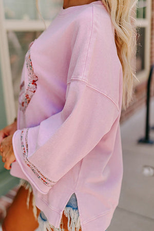 Dusty pink sweatshirt with floral peace sign detail and embellished cuffs.