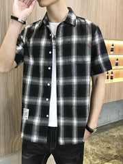 Black plaid short sleeve button-down overshirt with white t-shirt and jeans.