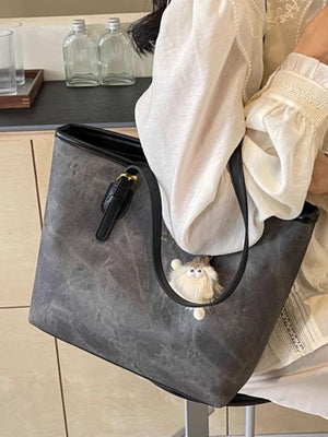 Distressed dark gray pu leather tote bag with buckle detail and fluffy charm.